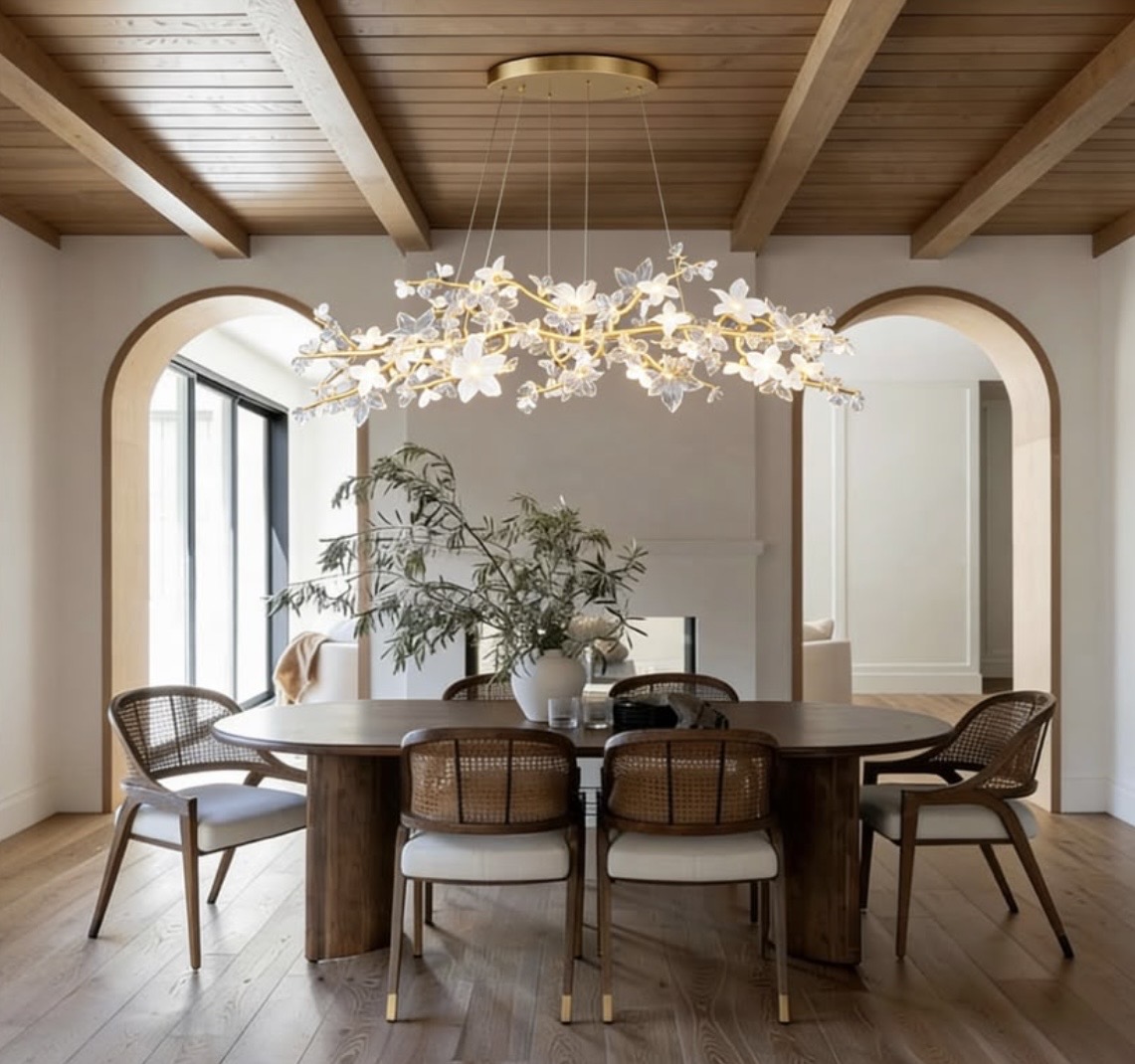 Dining room with a wide gold floral branch chandelier, glowing white flowers and two arched openings